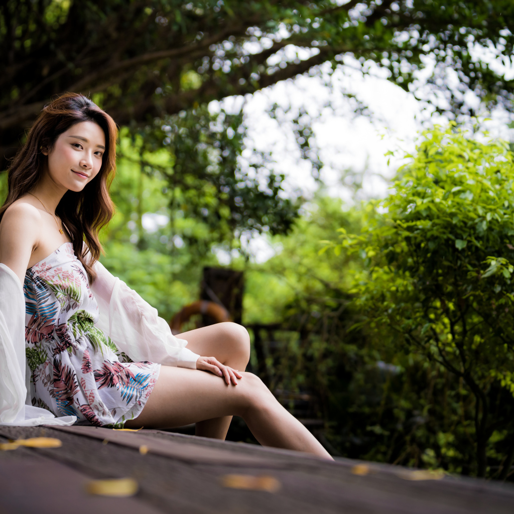 Милая девушка азиатка сидит на мосту