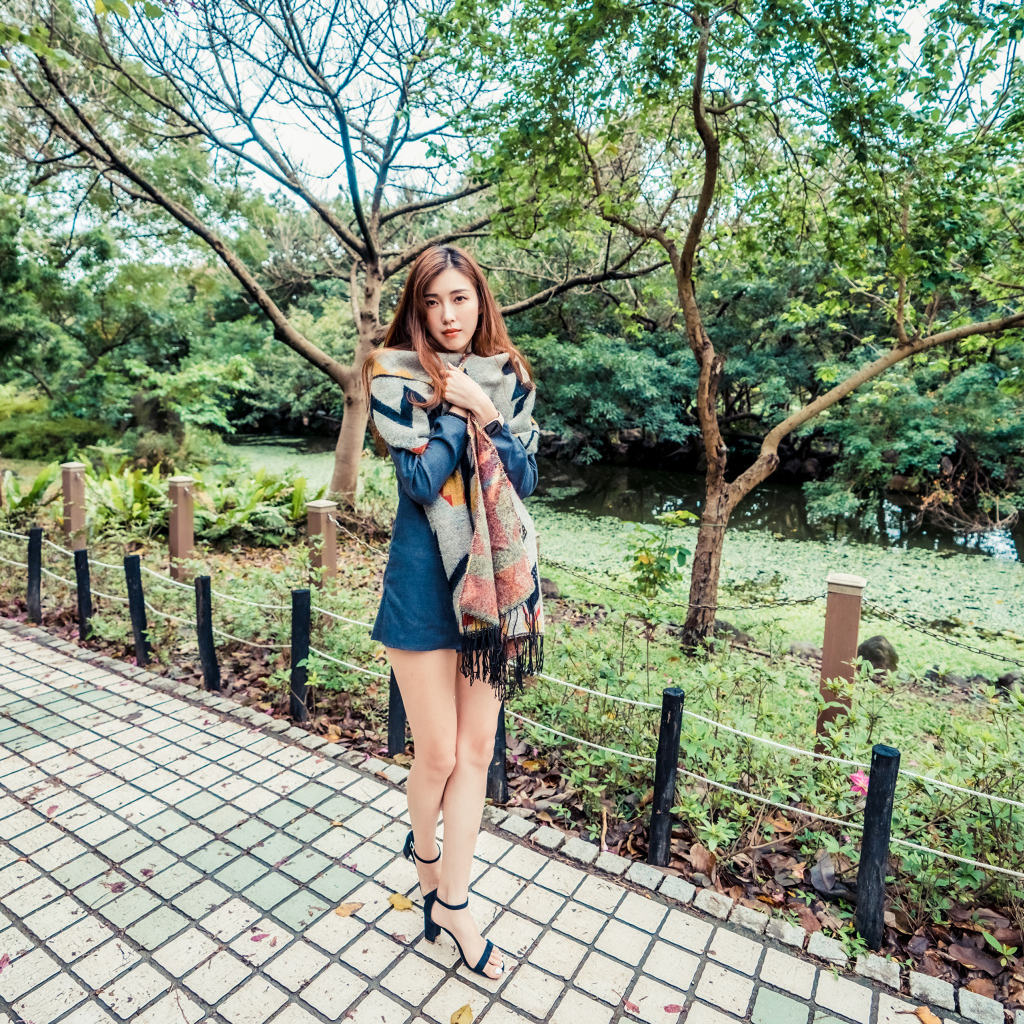 Милая девушка азиатка стоит в осеннем парке 