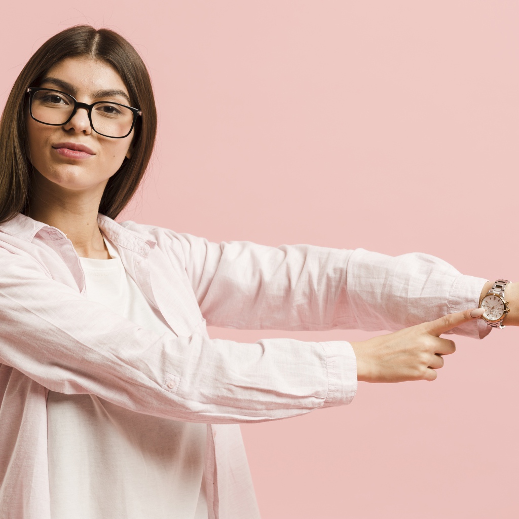 Girl with a watch on her hand on a pink background