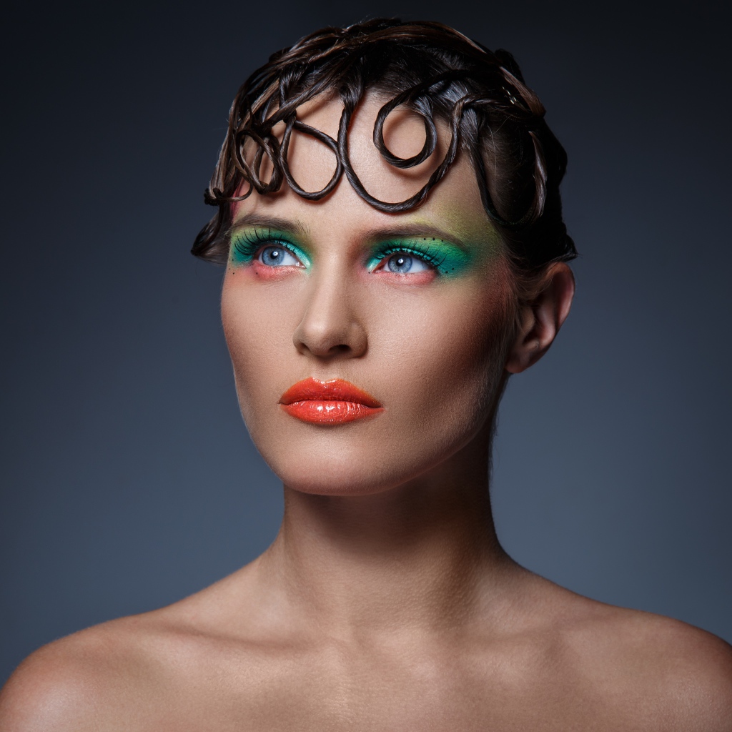 Девушка с ярким макияжем на сером фоне 