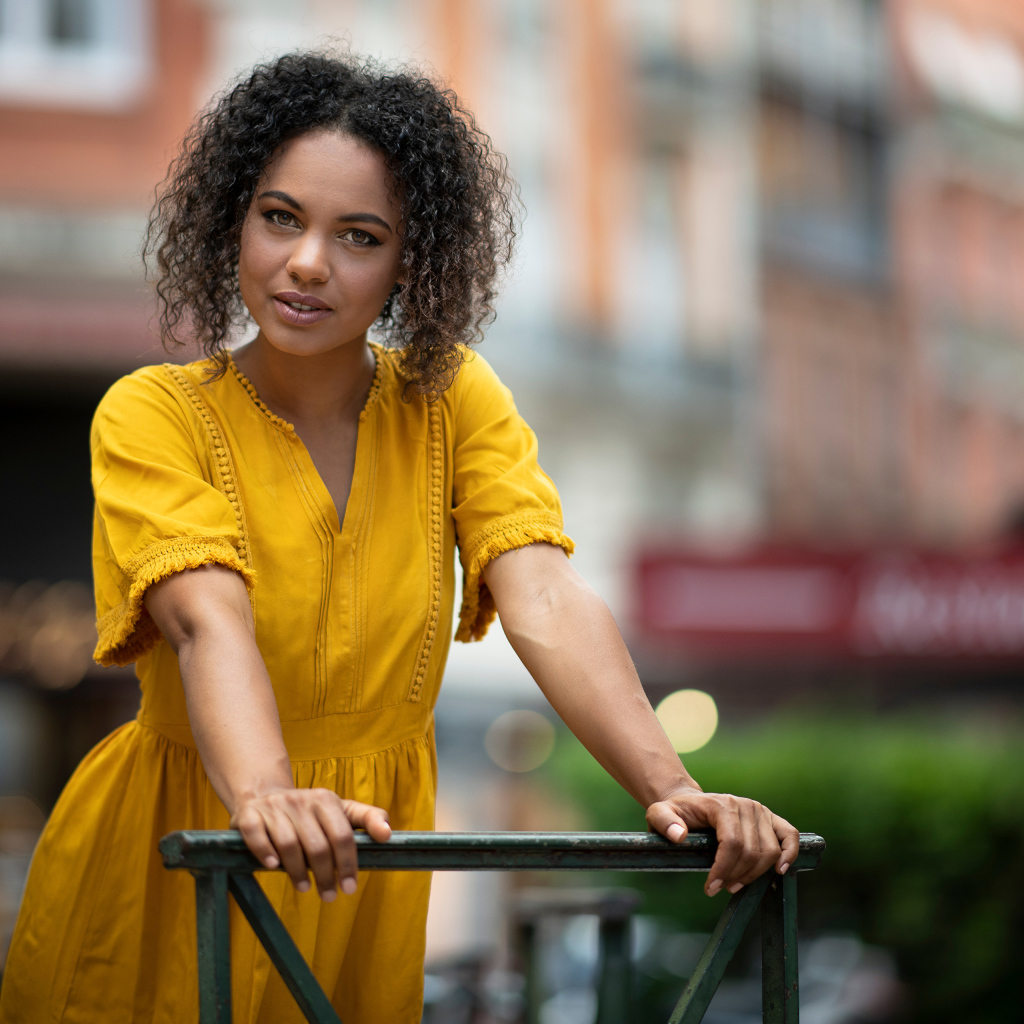 Девушка с кудрявым волосами в желтом платье