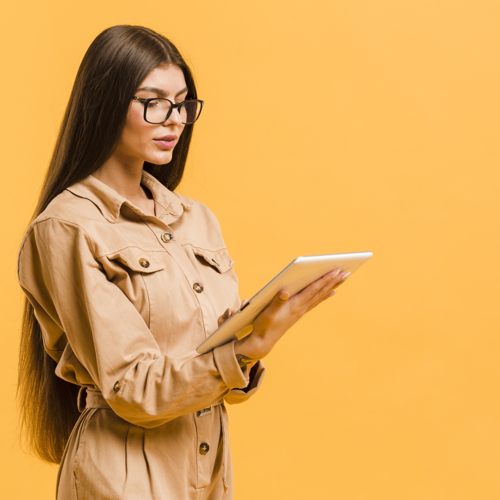 Девушка с планшетов руках на желтом фоне