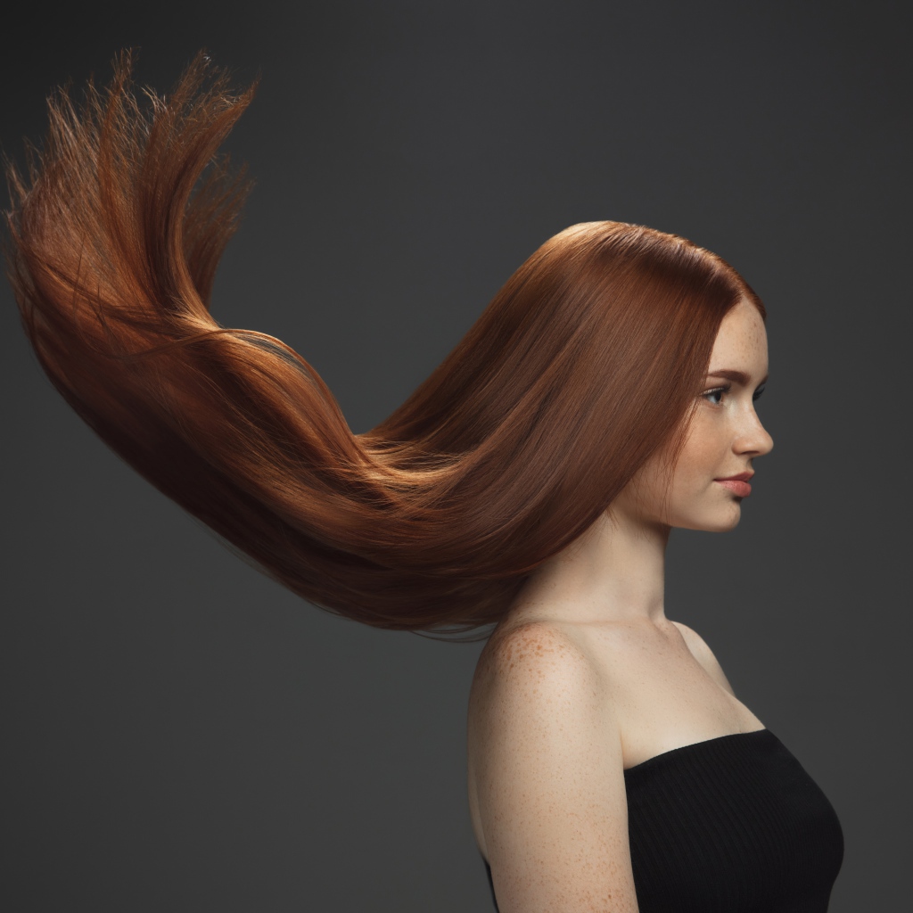 Волосы подняты вверх у красивой девушки на сером фоне