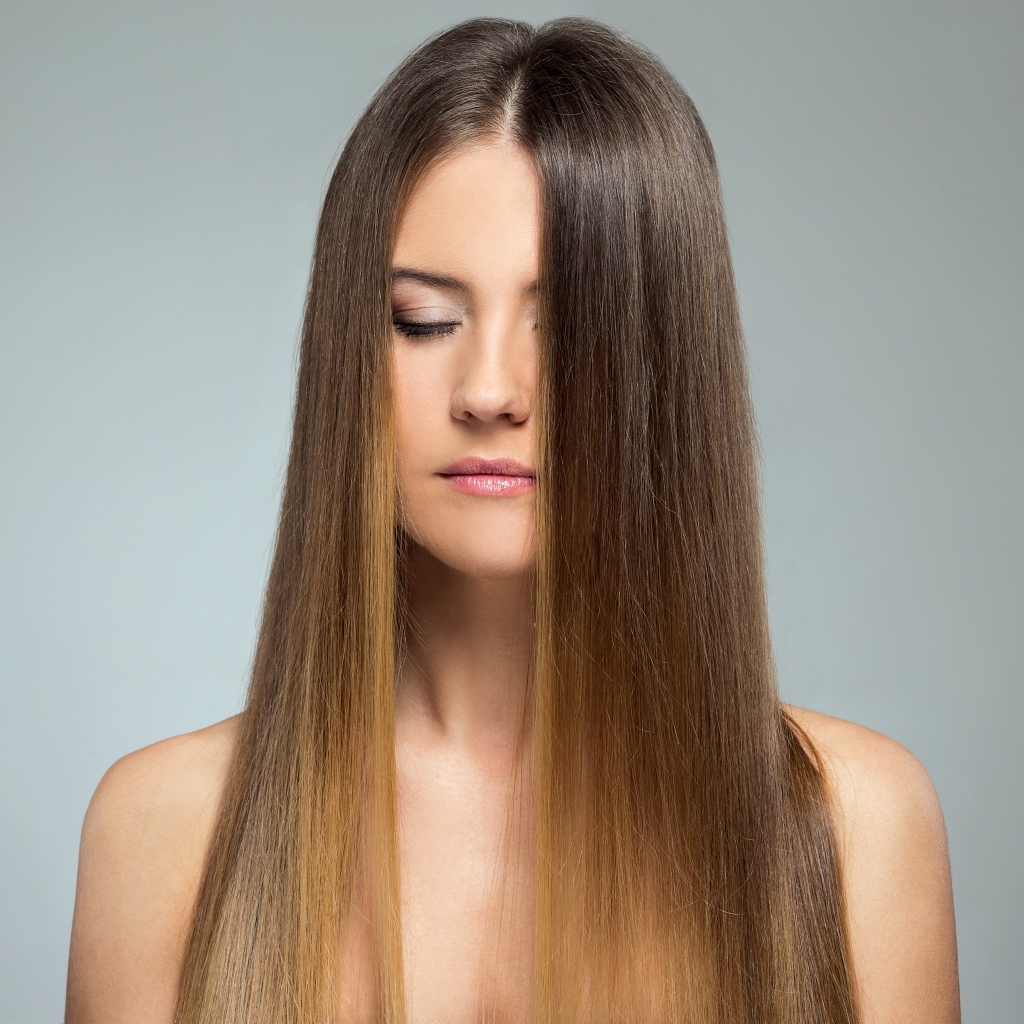 Длинноволосая шатенка с закрытыми глазами на сером фоне 