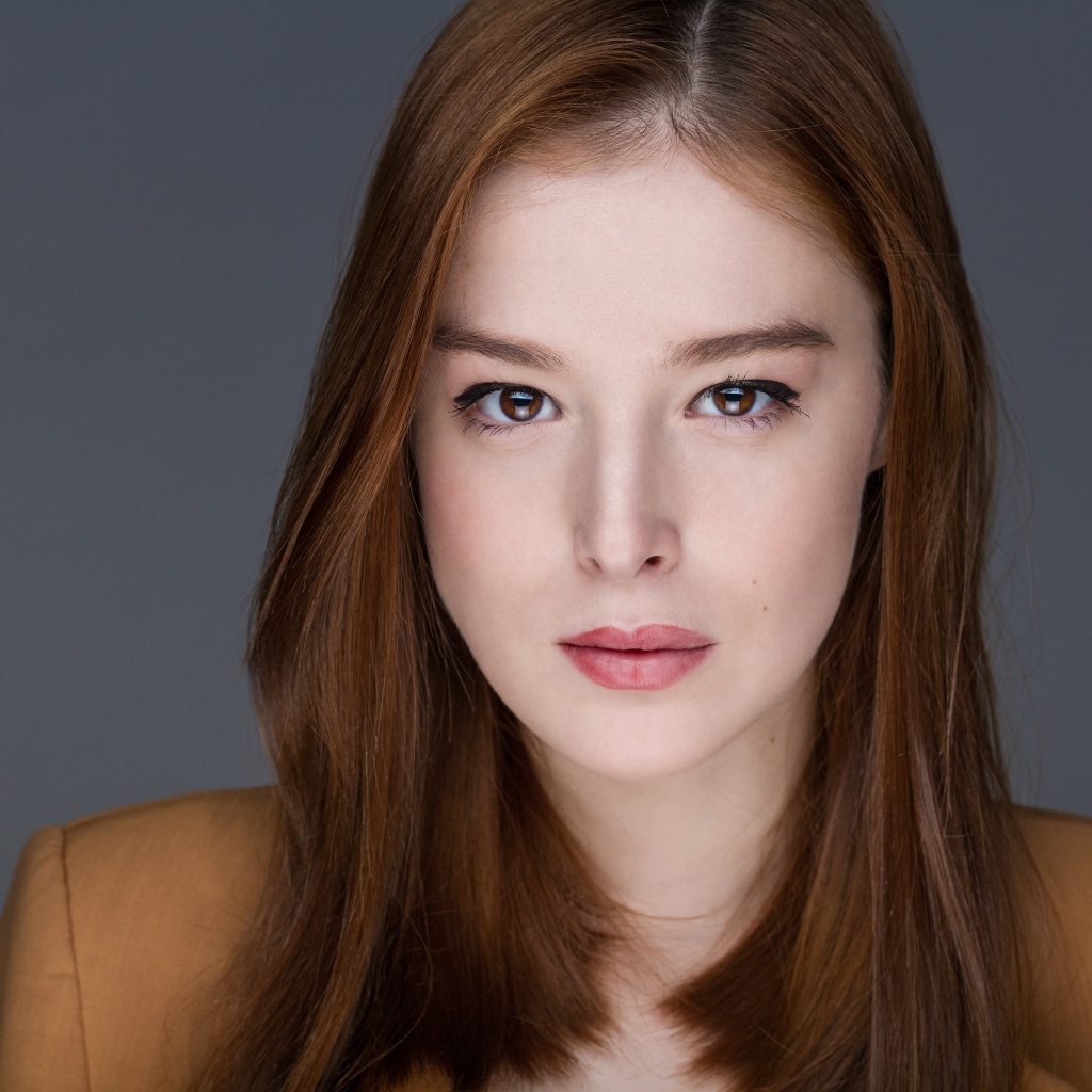 Рыжеволосая  молодая девушка на сером фоне