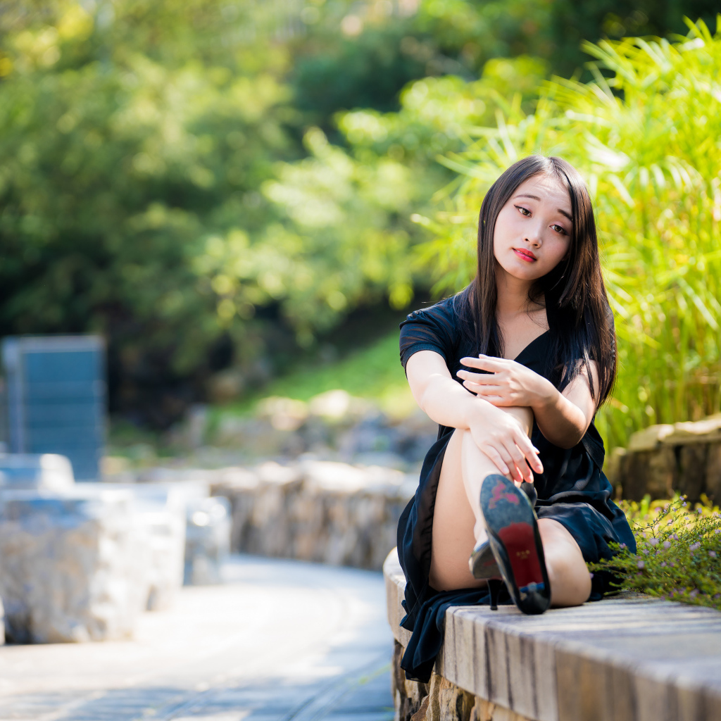 Грустная девушка в черном платье отдыхает в парке