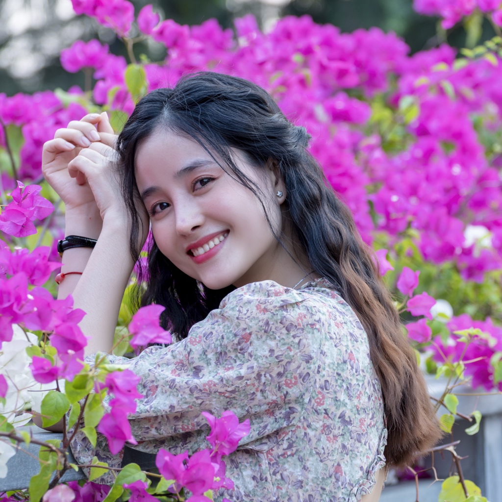 Улыбающаяся девушка азиатка на фоне розовых цветов