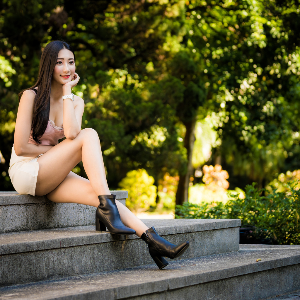 Улыбающаяся азиатка сидит на ступеньках