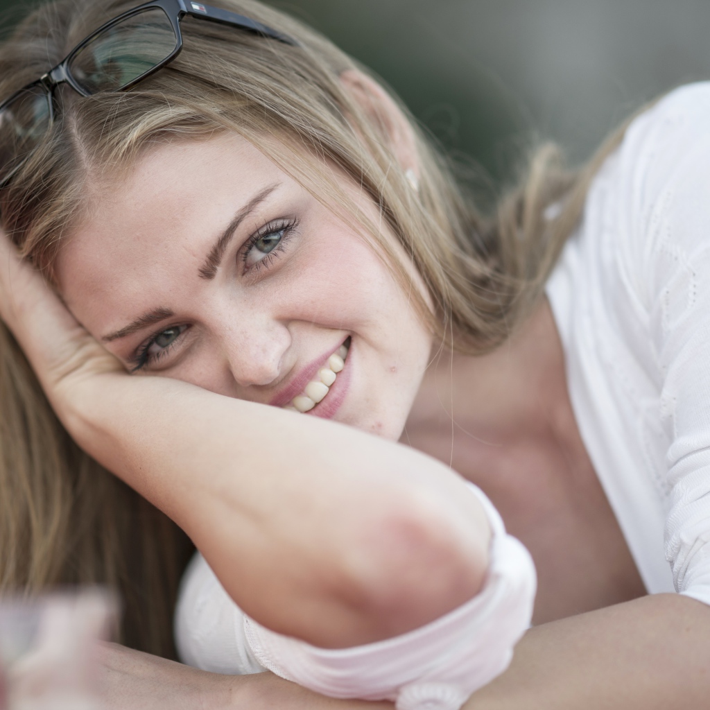 Улыбающаяся девушка блондинка с очками на голове