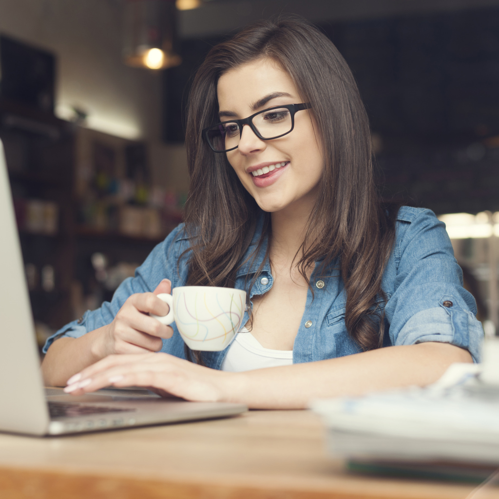 Улыбающаяся девушка в очках с ноутбуком