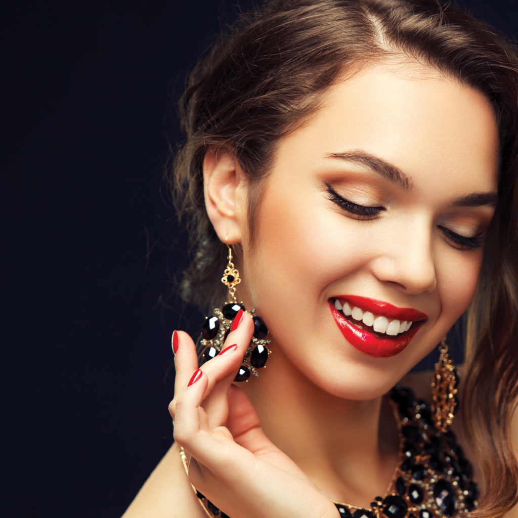 Улыбающаяся девушка носит украшения с черными камнями
