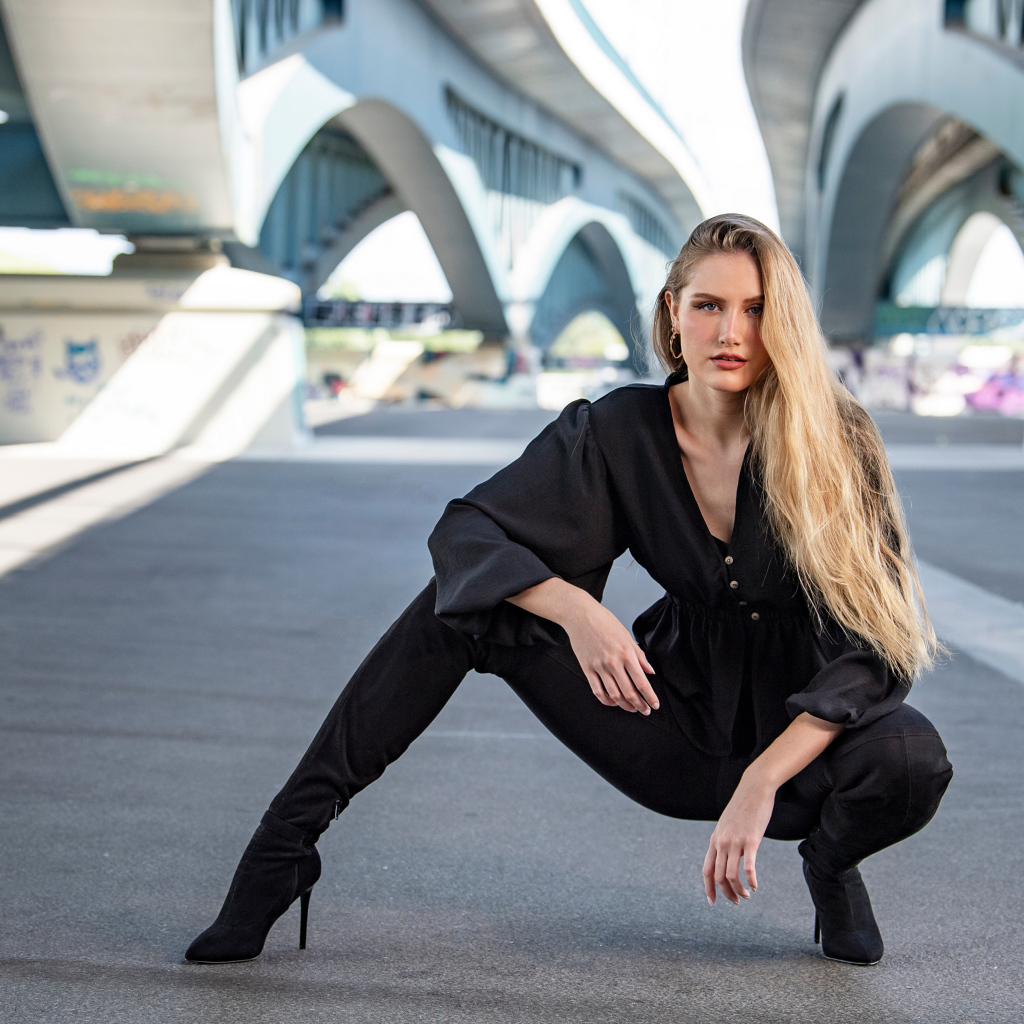 Стильная девушка в черном костюме под мостом