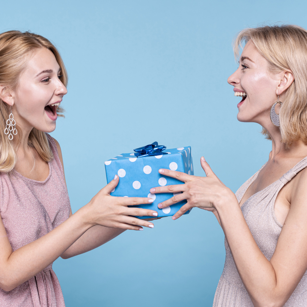 Две подруги блондинки с подарком на голубом фоне