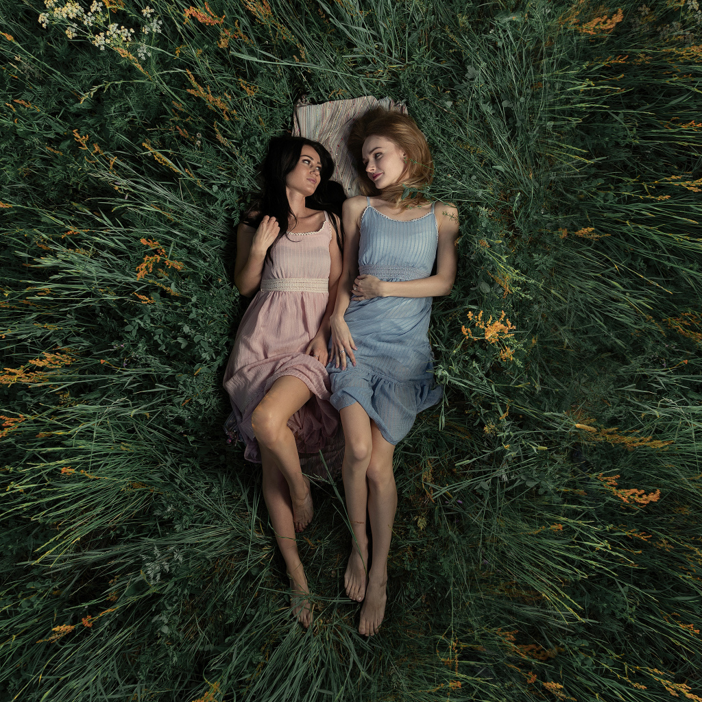 Two girls lie in the tall grass