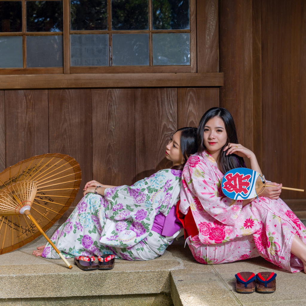 Две молодые девушки в кимоно сидят на полу