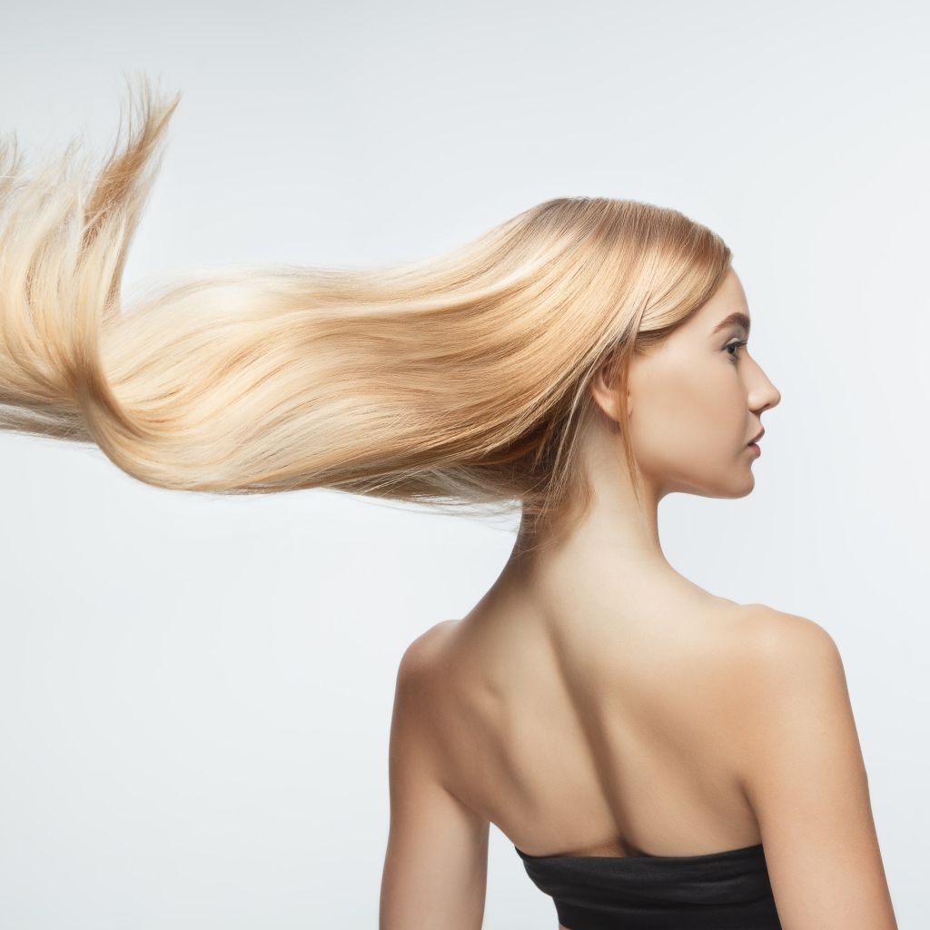 Белые волосы девушки развиваются на белом фоне 