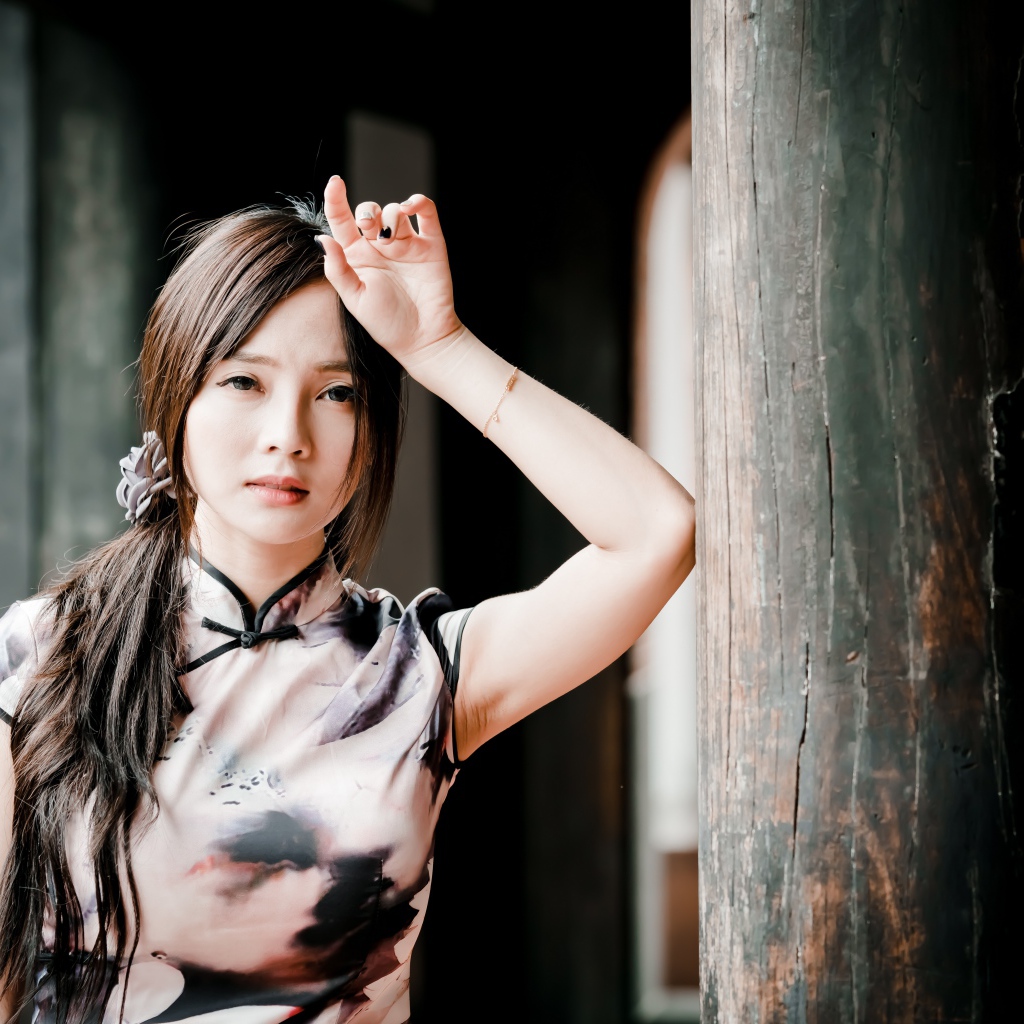 Молодая девушка азиатка стоит у столба 