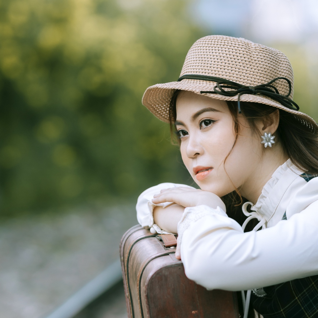 Молодая азиатка в шляпе с чемоданом