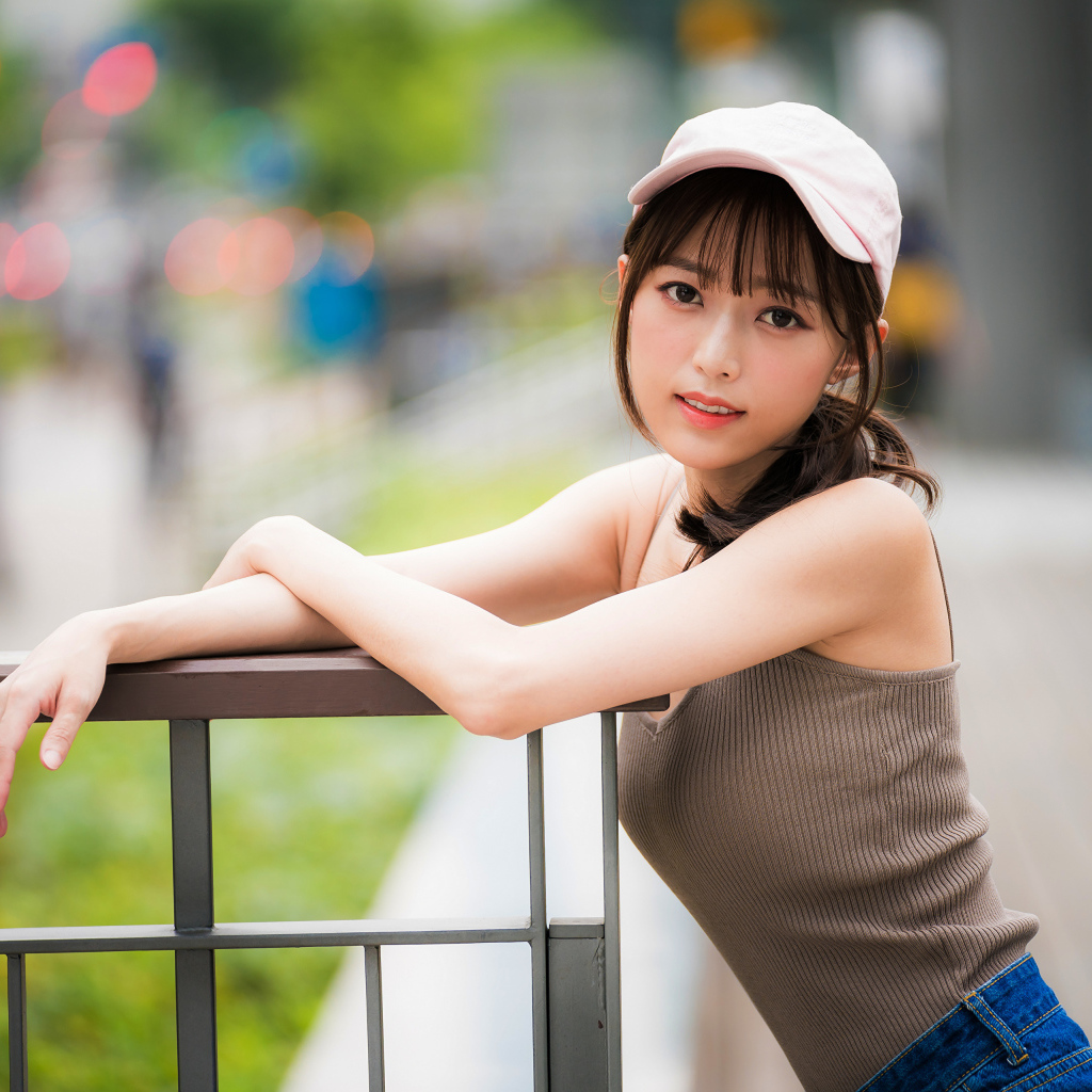 Молодая азиатка в кепке у перил 