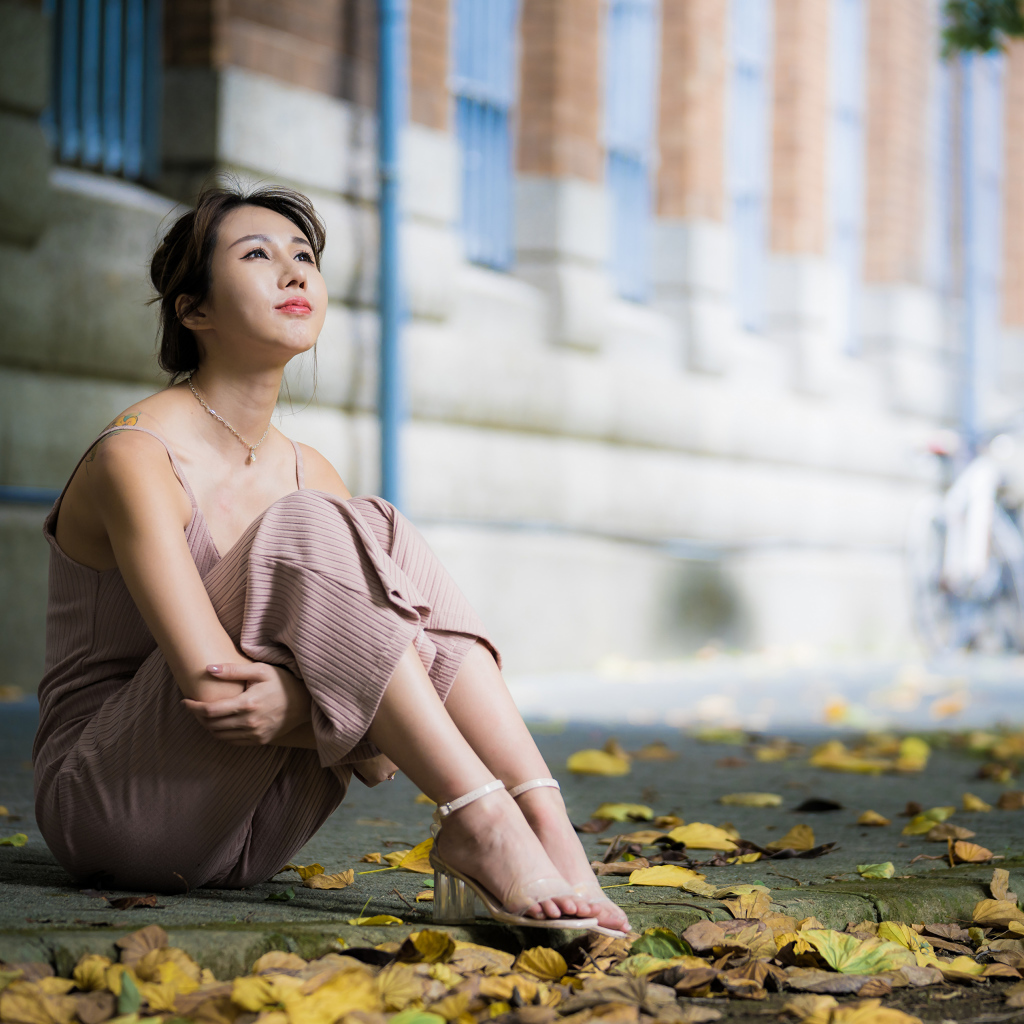 Молодая девушка азиатка сидит на земле с листьями 