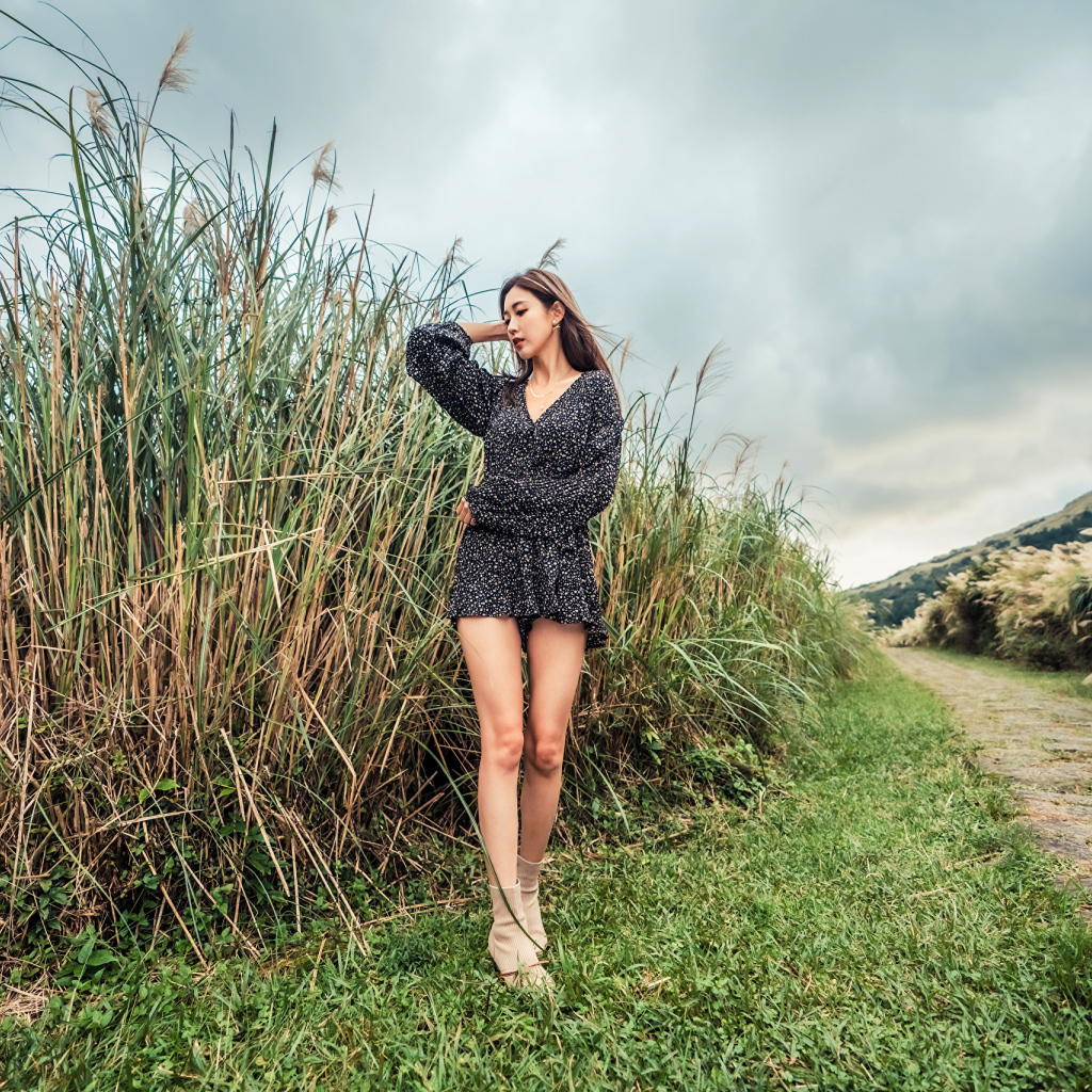 Молодая девушка азиатка стоит у зеленой травы