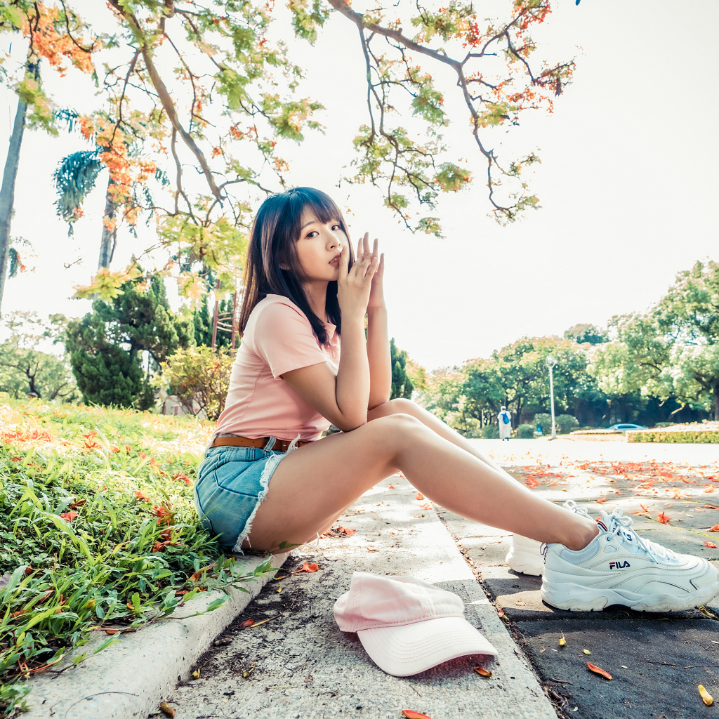 Молодая азиатка сидит на земле в осеннем парке