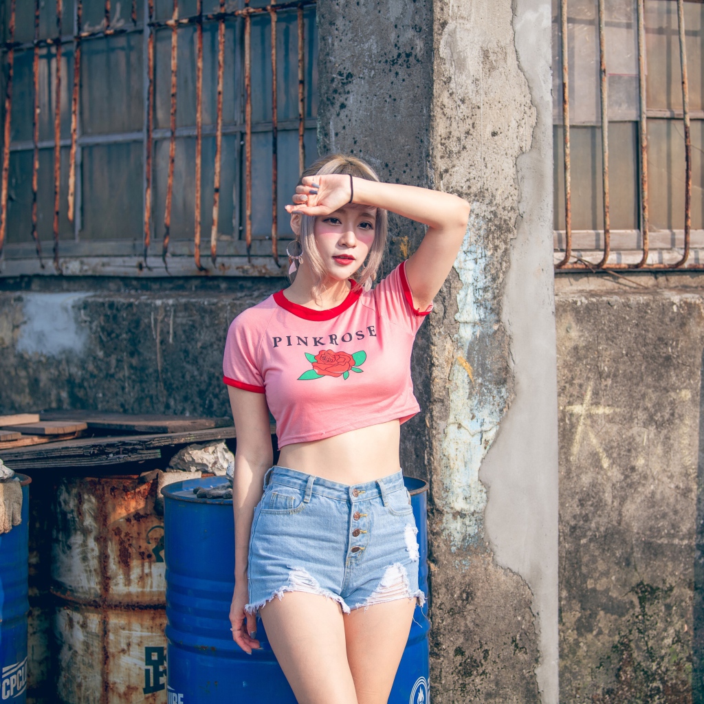 Молодая азиатка стоит у стены 