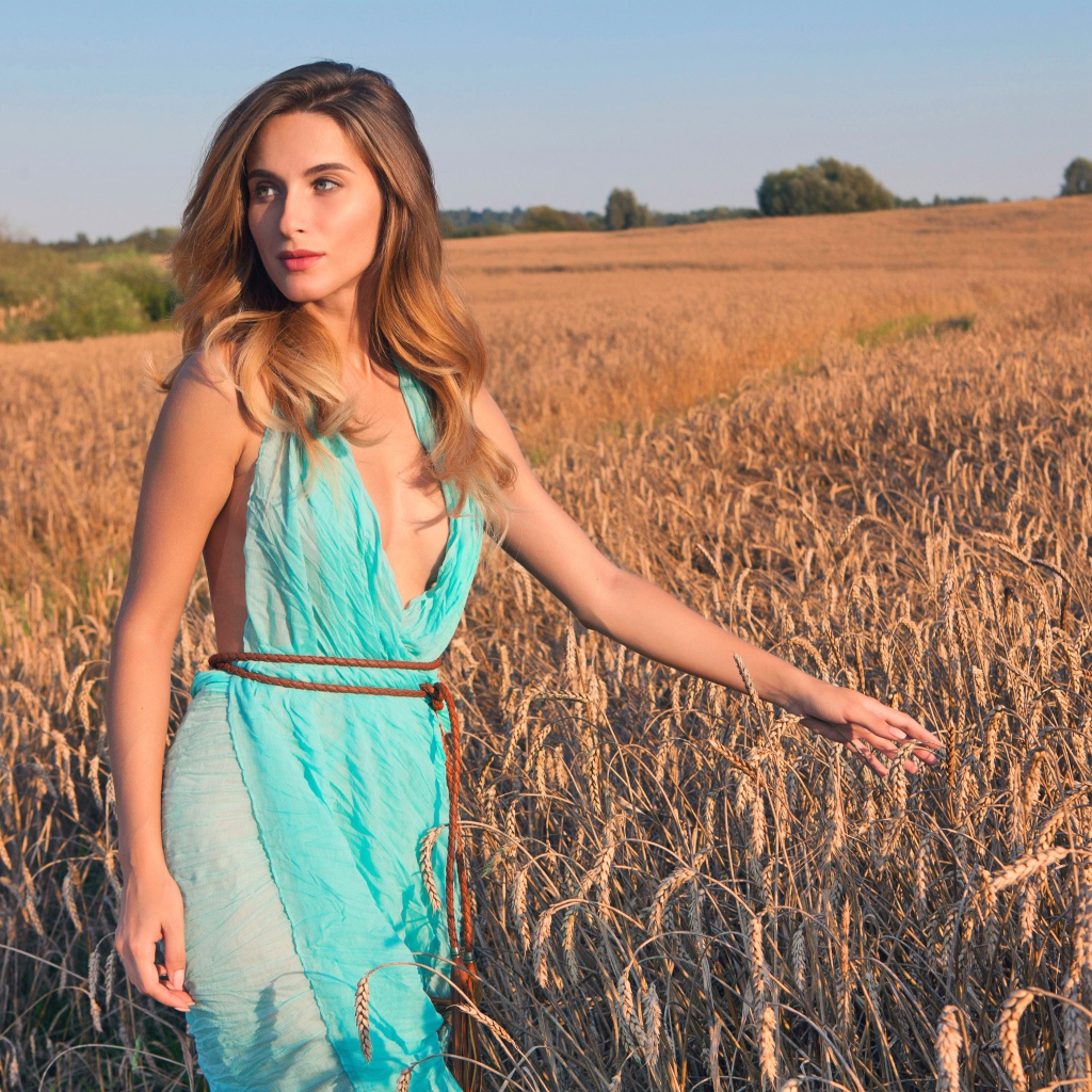 Молодая девушка в голубом платье на поле с пшеницей 