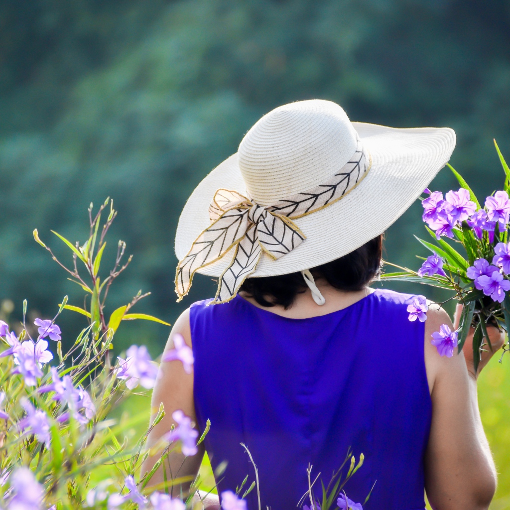Молодая девушка в шляпе с букетом цветов 