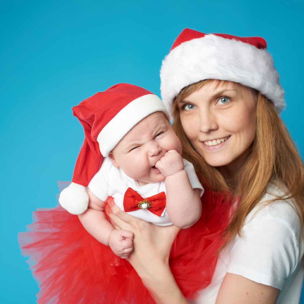 Девушка с ребенком в новогодних костюмах на голубом фоне