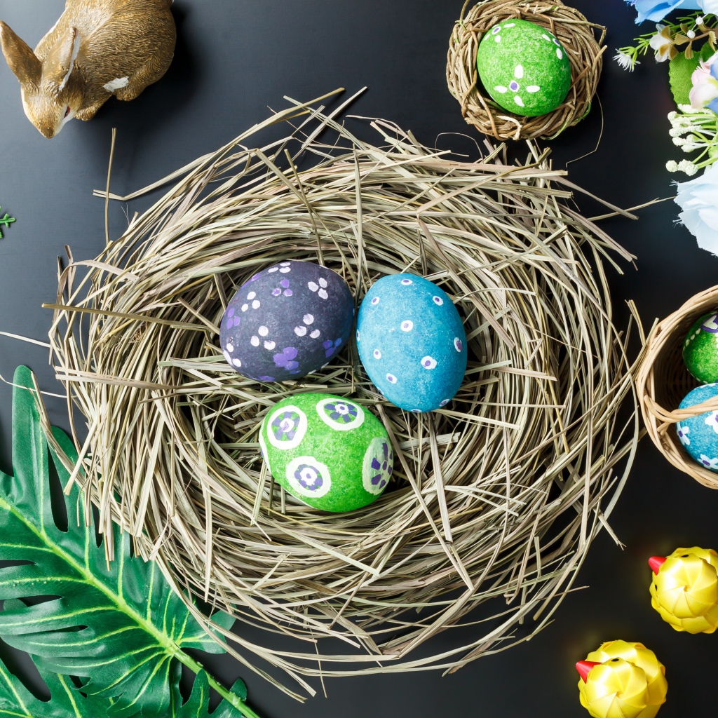 Яркие пасхальные яйца на столе в гнезде