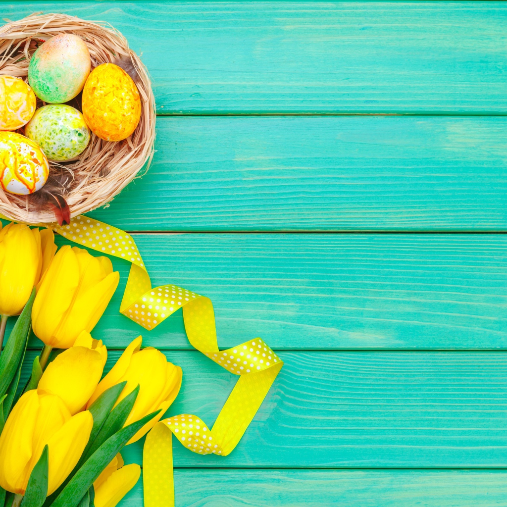 Разноцветные пасхальные яйца  и букет желтых тюльпанов на голубом фоне