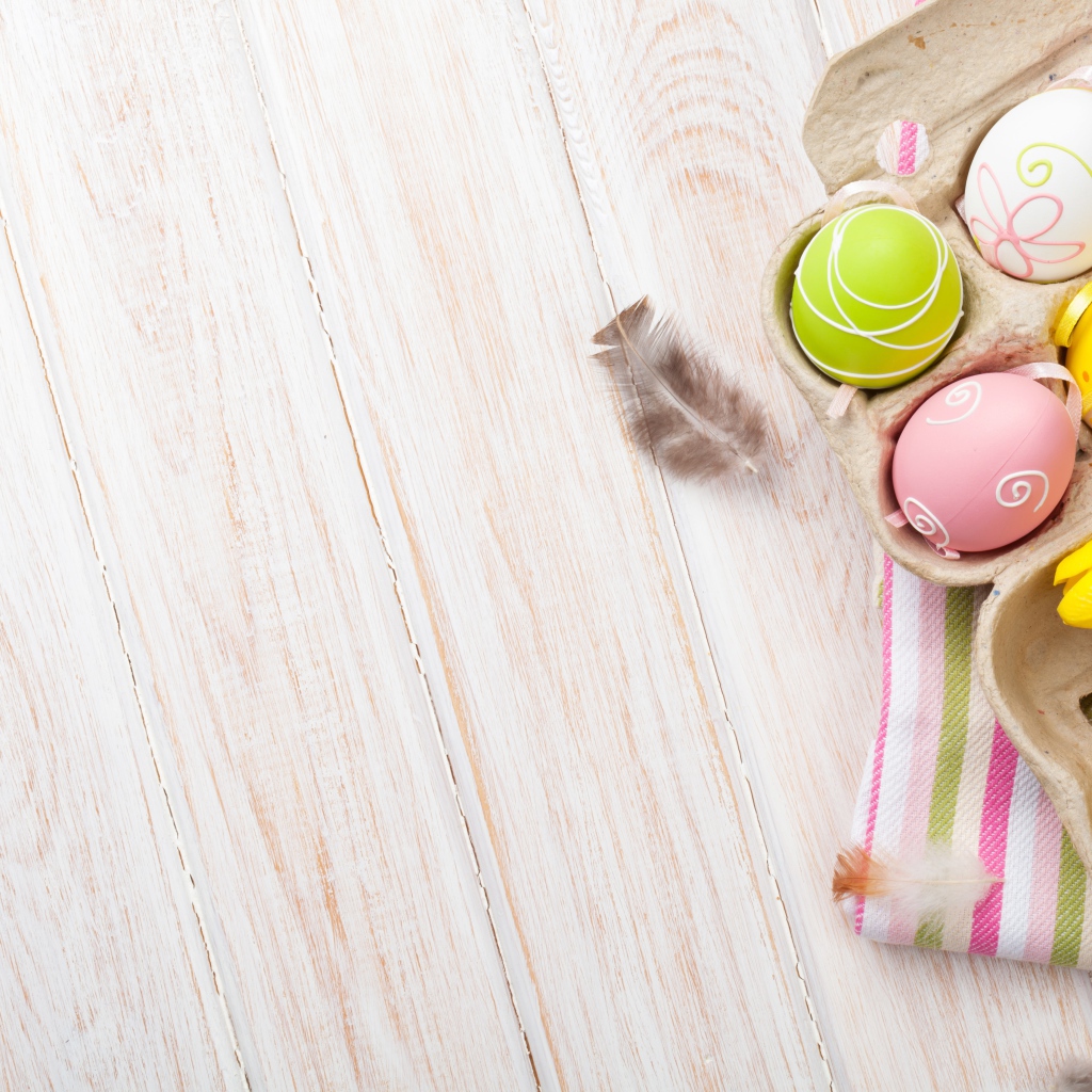 Крашеные пасхальные яйца на столе с тюльпанами