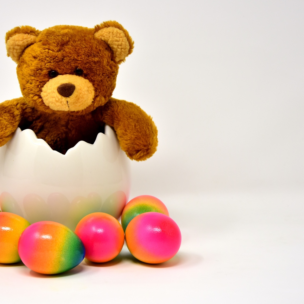 Медвежонок с яркими пасхальными яйцами на сером фоне
