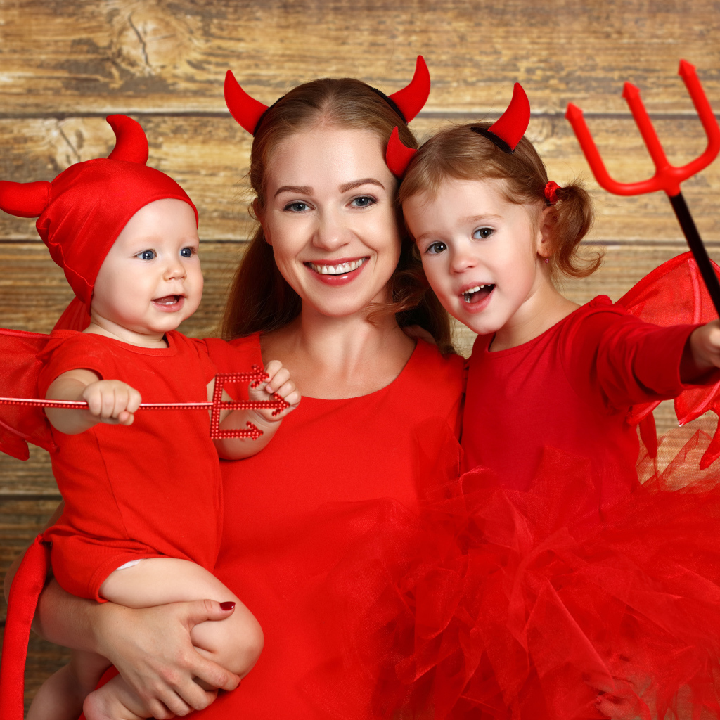 Женщина с двумя детьми в красных костюмах на Хэллоуин