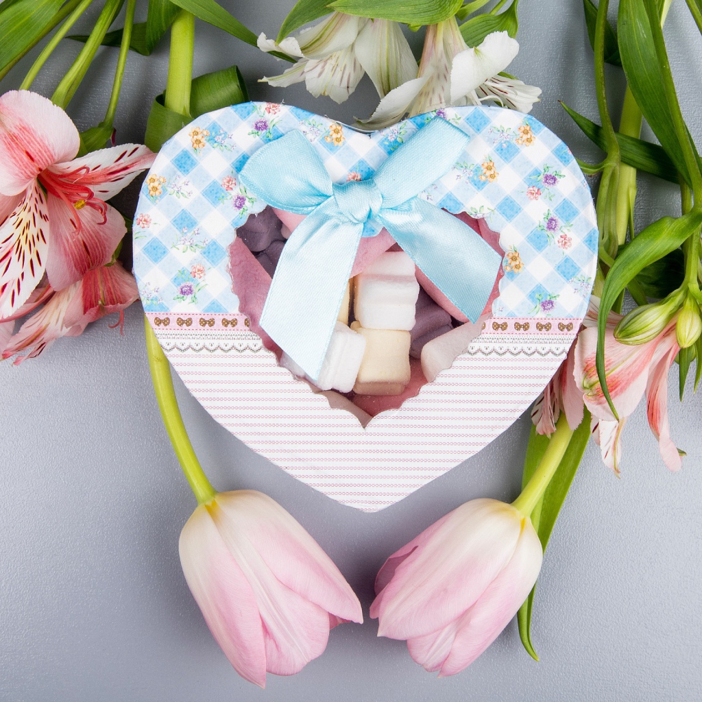 Коробка конфет в форме сердца и цветы на сером фоне на 8 марта