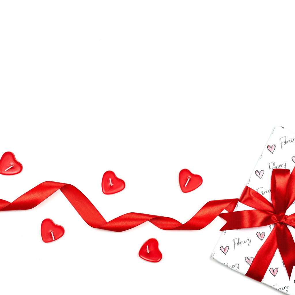 Подарок с красной лентой и свечами на белом фоне на День Святого Валентина