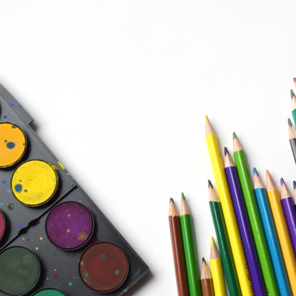 Разноцветные карандаши и краски на белом фоне
