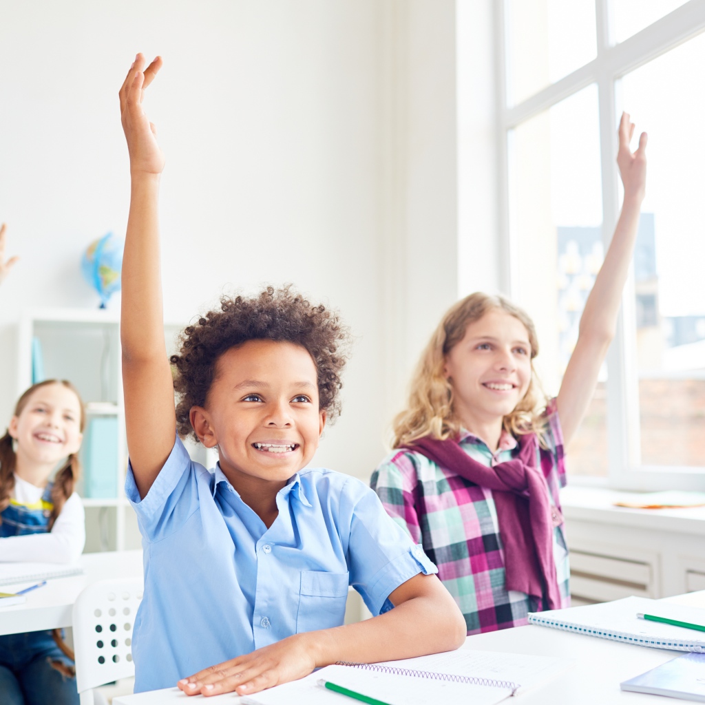 Дети школьники с поднятой  рукой в классе на 1 сентября 
