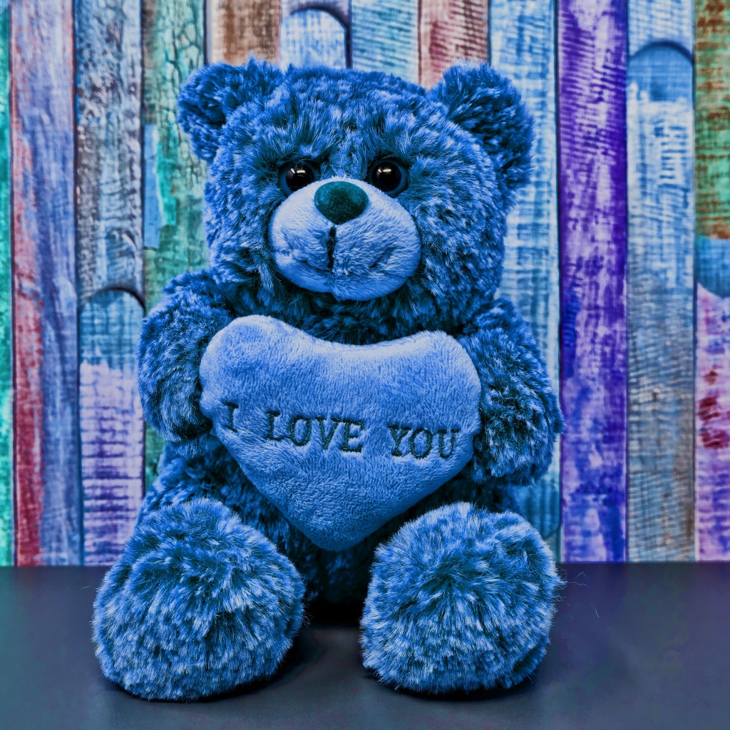 Синий медведь с сердцем на фоне забора