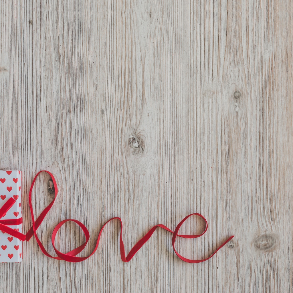Коробка с подарком  и надпись любовь красной лентой на деревянном фоне