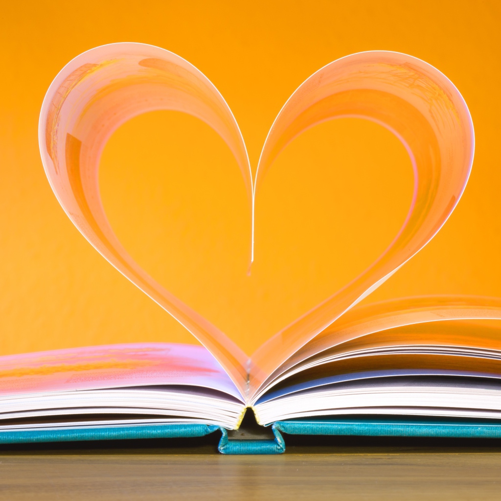Сердце из страниц книги на оранжевом  фоне  