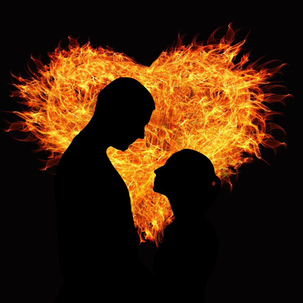 Loving couple on the background of a fiery heart on a black background