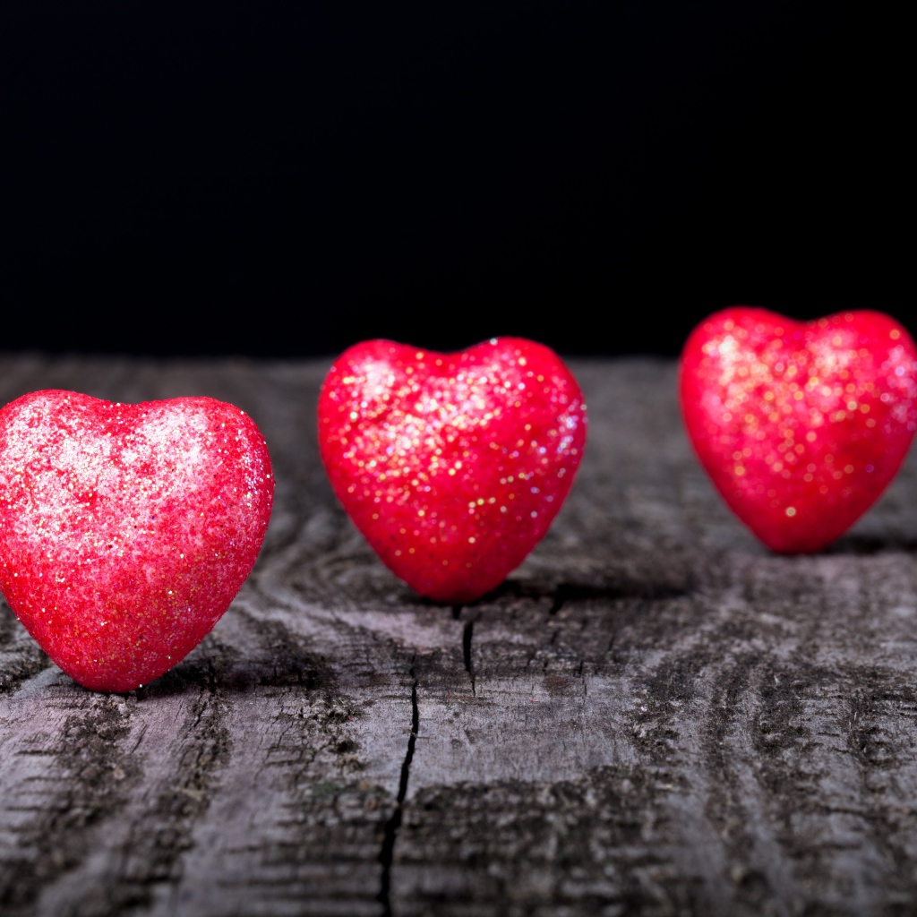 Блестящие красные сердечки на деревянном столе