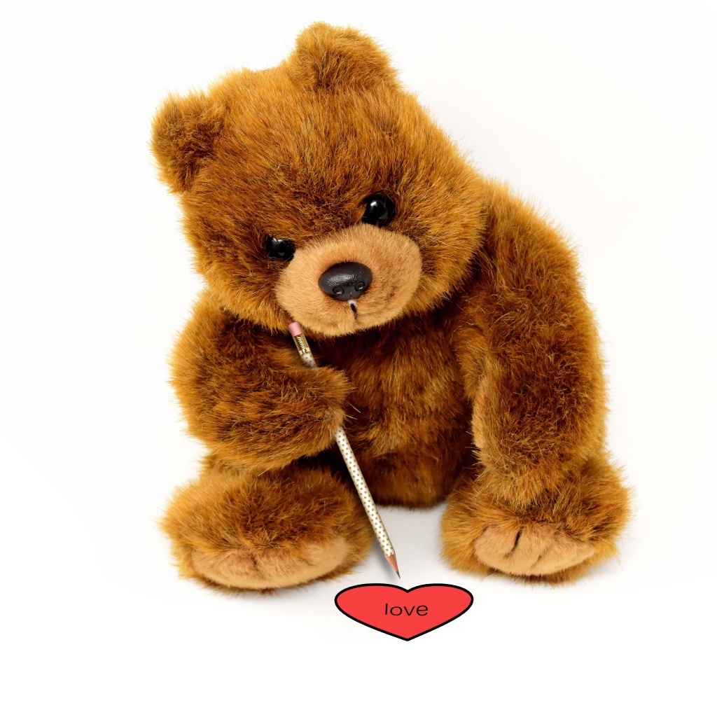 Toy teddy bear draws a heart on a white background