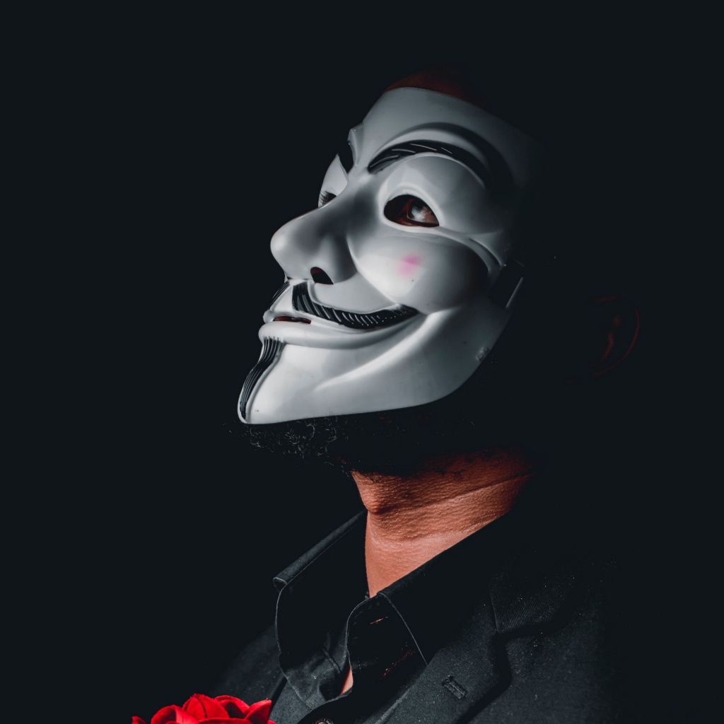 Мужчина в белой маске анонимуса на черном фоне 