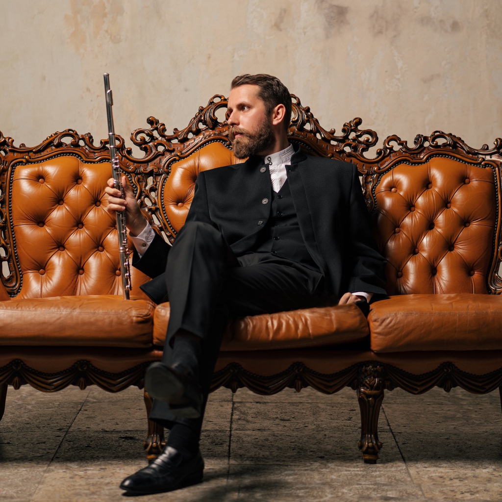 Солидный мужчина в костюме сидит на диване