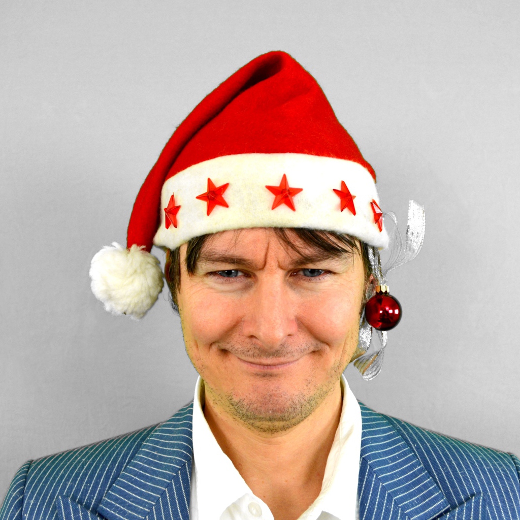 Голубоглазый мужчина в новогодней шапке на сером фоне 