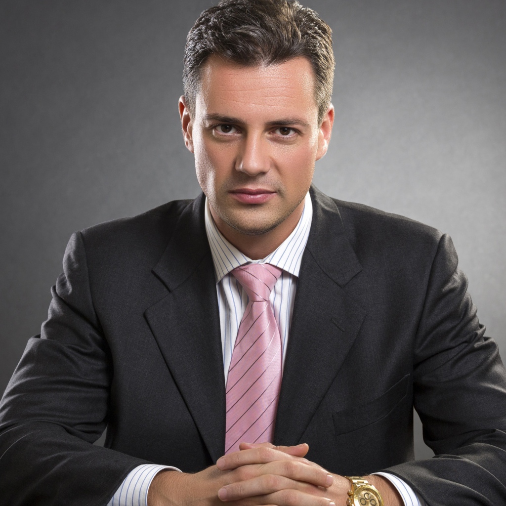 Деловой мужчина в костюме на фоне серой стены 