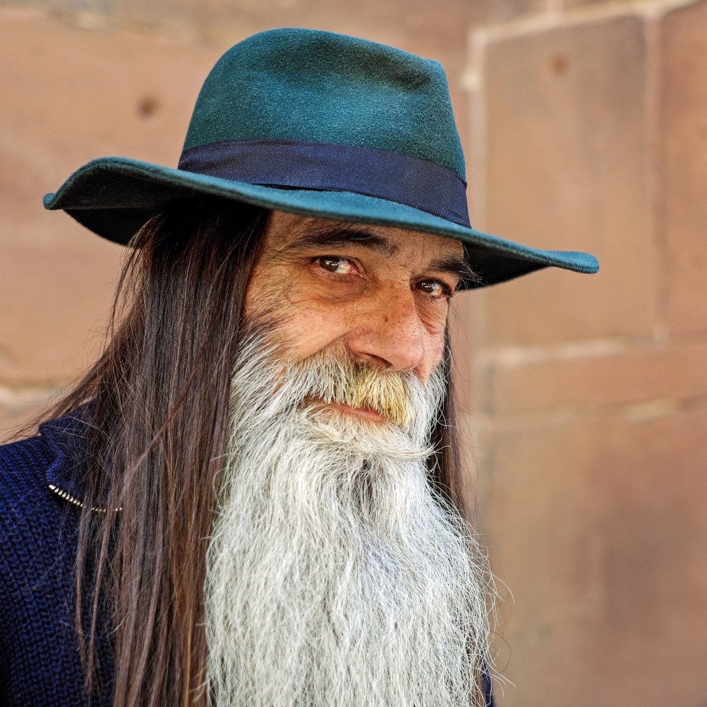 Пожилой мужчина с длинными волосами в шляпе 